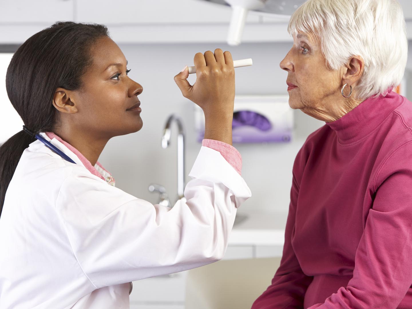 Female Doctor Examining Senior Female Patient's Eyes